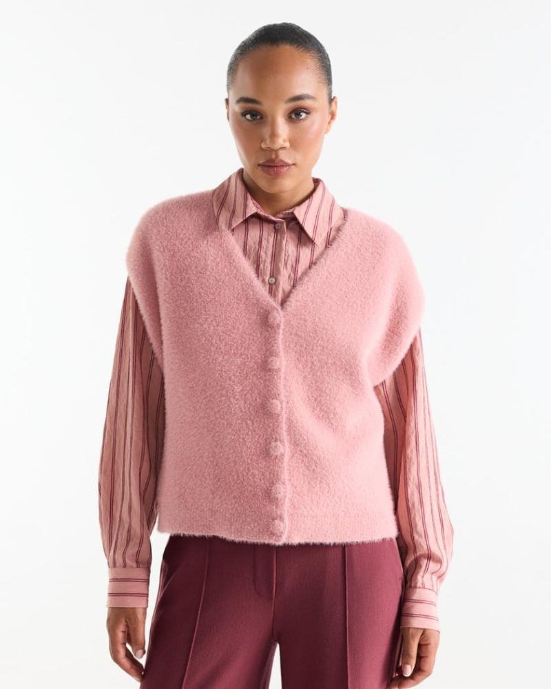 Model wearing the Chelsie pink fluffy sweater vest layered over a striped blouse