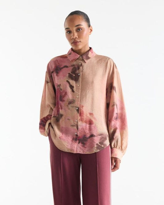 Model wearing pink watercolour print blouse with classic collar and wine-red trousers