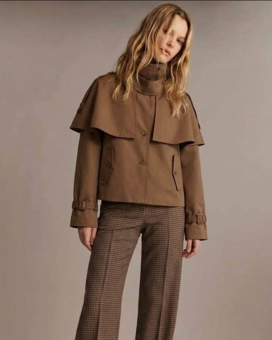 Model wearing a brown boxy jacket with cape detail over checked trousers